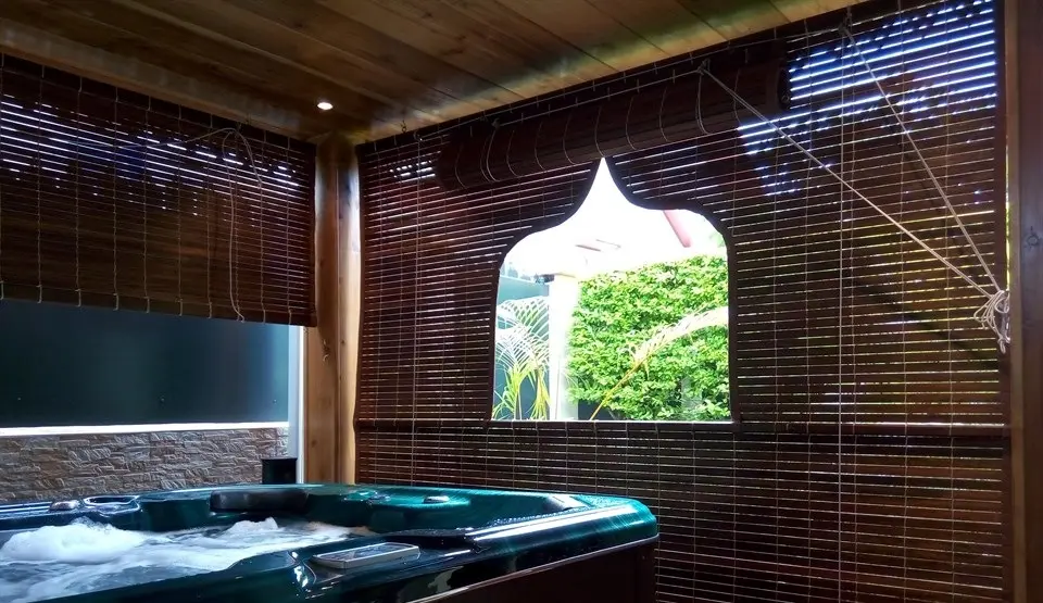 Coin spa fermé par des stores sombres, avec une fenêtre découpée en arche sur le jardin