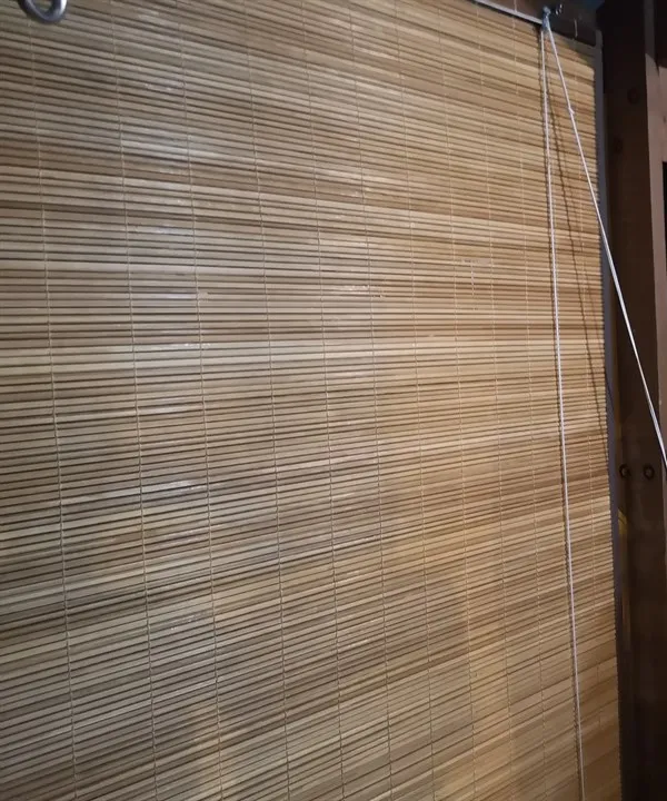 Gros plan sur un store à fines lames de bois couleur miel, posé par Store Péi